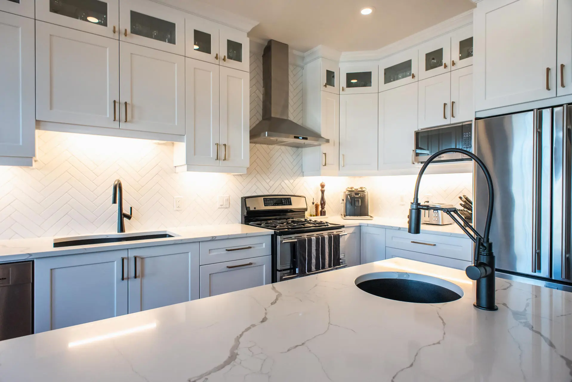 Modern kitchen with white cupboards, dark island and gold accents.